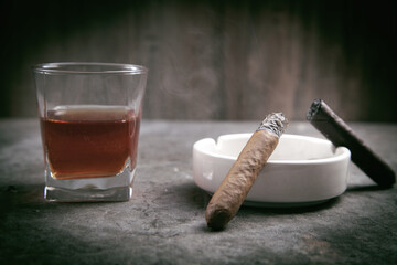 Glass of whisky, ashtray and cigars on the table.