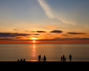 Silhouetted people at sunset on the Welsh coast - family playing in the golden light