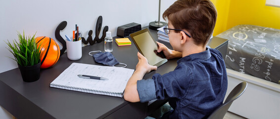 Teenager doing homework with a tablet in his room