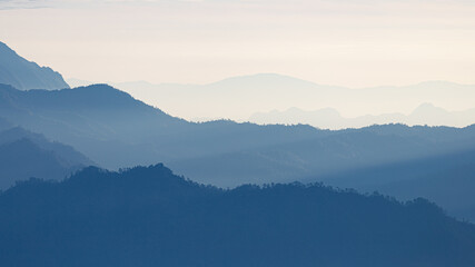 Natural scene of blue mountain range covered by mist and fog.