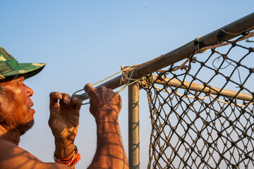 Fishermen raising fish repairing nets for fish farming ponds.