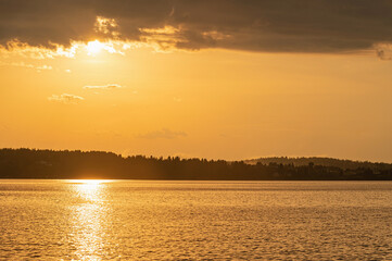 The sun's rays break through the dark clouds after a storm over the river.