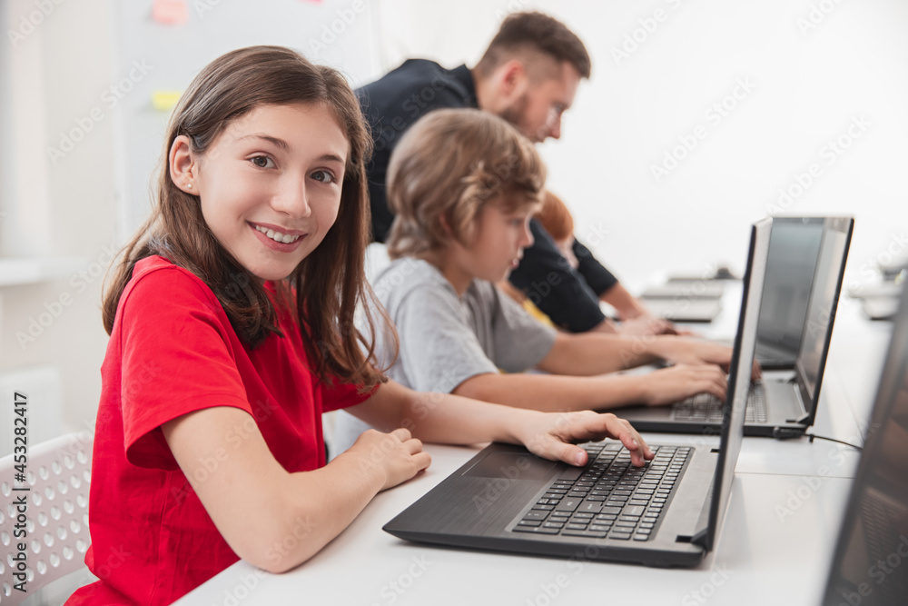 Wall mural smart kids studying programming in classroom