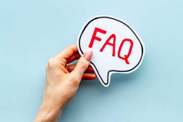 Hands with faq word on paper bubble. Frequently asked questions concept