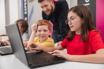 Children with teacher working on laptops