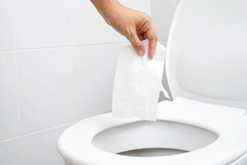 close up hand holding a tissue to be thrown into the toilet bowl. Can not drain water of toilet...