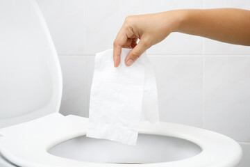 close up hand holding a tissue to be thrown into the toilet bowl. Can not drain water of toilet...