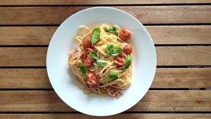 A plate of Feta Pasta with cherry tomatoes on a wooden table. 