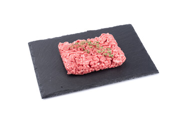 Minced meat with caraway seeds on black slate stone board isolated on white background.