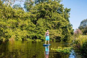 Fototapeta na wymiar middle aged man paddle boarding on a river