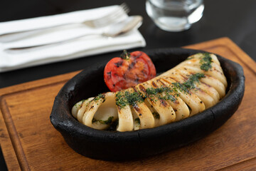 Grilled squid with tomatoes on a clay plate. Selective focus.