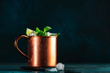 Abwaschbare Fototapete Moskau Moscow mule cocktail in copper mug with lime, ice, ginger beer, vodka and mint. Deep blue background