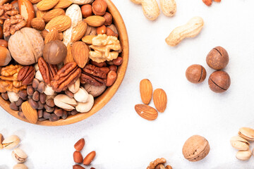 Nut mix in bowl. Almonds, hazelnuts, walnuts and other. Healthy food snack mix on white table, top...