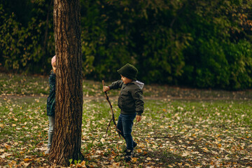 a boy and a girl play hide-and-seek in an autumn park
