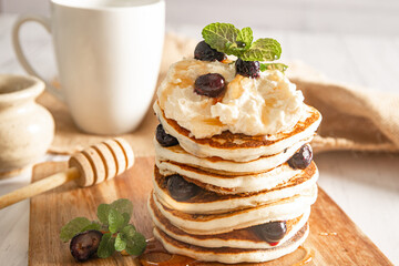 Pile of freshly cooked pancakes with blueberries on white background, morning breakfast meal