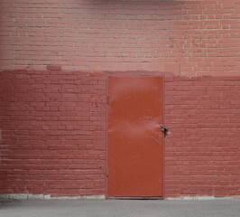 A brown metal door in a painted brick wall
