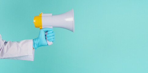 Megaphone in hand.Man wear doctor gown and blue medical glove on mint green or Tiffany Blue ...