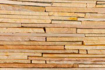 Decorative wall of fine stones, with light colored horizontal lines, highlighting its texture
