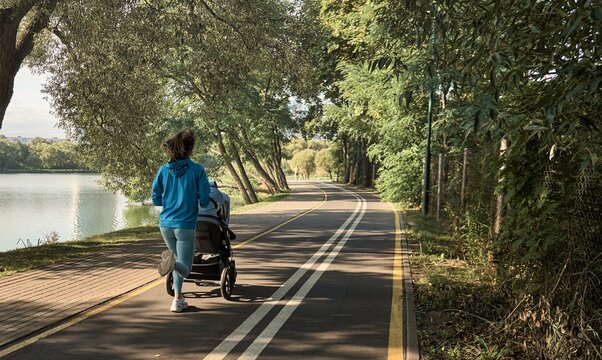 Active mother jogging. Jogging or power walking woman with a baby stroller in morning. Mother with child in stroller running