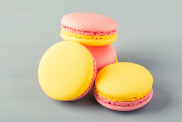 Pink yellow macaroons cakes on gray blue table background, place for text, trendy minimalism style, selective focus