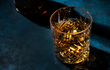 Glass of golden scotch whiskey on dark bar table background, selective focus