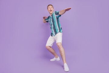 Portrait of excited crazy shocked astonished guy dance look empty space open mouth on violet background