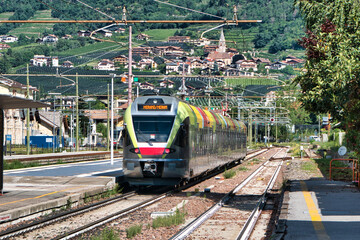 Ein farbenfroher Zug der italienischen Eisenbahn fährt in den Bahnhof von Meran ein