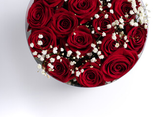 A bouquet of bright red roses with white dried flowers in a round box top view