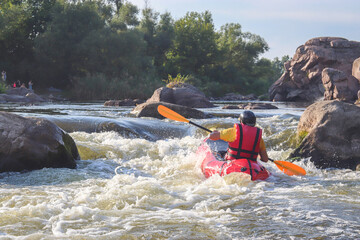 A man rowing inflatable packraft on whitewater of mountain river. Concept: summer extreme water sport,  active rest, extreme rafting.