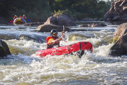 A man rowing inflatable packraft on whitewater of mountain river. Concept: summer extreme water sport,  active rest, extreme rafting.