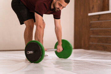 Gripping a barbell young man standing gripped a black and green weight set, equipment for weight...