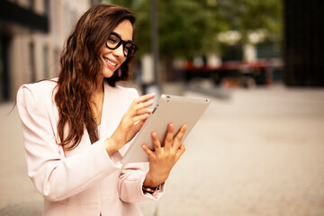 Young businesswoman using tablet outdoors. Beautiful young woman having video call