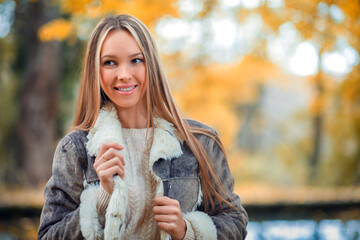 Outdoor autumn close-up portrait of a young beautiful woman in a warm jacket made of faux fur.