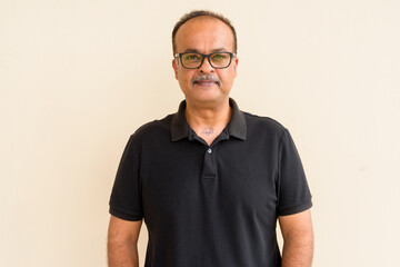 Portrait of handsome Indian man with mustache against plain wall