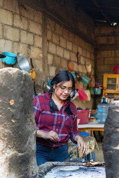 Vertical Shot Of A Young Hispanic Lady Making Tortillas On An Old Stove In The Kitchen