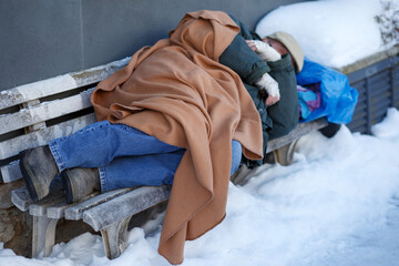 Obdachloser Mann schläfft im Winter auf einer Sitzbank - obrazy, fototapety, plakaty