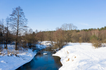 Drone shot flying on forest and river in winter.