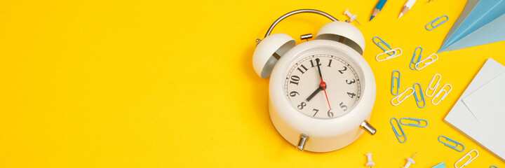 Concept of education top view white clock and accessories stationery learning in library at school yellow background