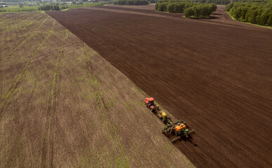 Farmer in tractor preparing land for sowing, cultivation and plows field for planting, Aerial top view rural