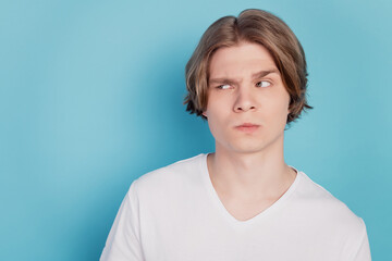 Photo of young man hesitate look empty space isolated over blue background