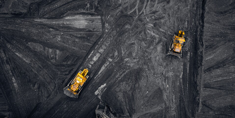 Loading coal, two yellow excavators handling anthracite in an open mine, aerial top view