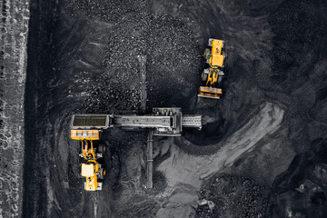 Aerial top view open mine, Yellow Excavator loads anthracite for crushing into coal crusher
