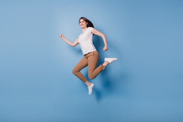 Fototapeta na wymiar Portrait of sporty energetic active runner lady jump hurry run on blue background