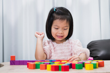 Happy pupil girl playing colorful wooden brick block on table. Back to school in funny. Practice...