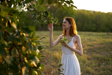 red-haired woman in a field near apple-tree fruits