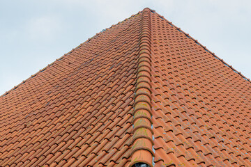 Old orange brick gable roof top under blue clear sky, Isosceles tiles background details, Shingles texture, Abstract geometric pattern, Roof brick material.