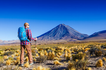 Hiker looking at view during a hiking trip with beautiful volcano landscape Atacama desrt. Chile