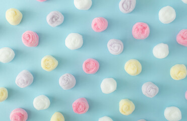 White, yellow, lilac and pink cotton balls against pastel blue background. Minimal natural concept. Flat lay.