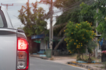 Rear side of silver pick-up car driving on the asphalt road in the city. During daytime.  with open brake light.