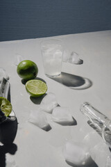 Lemonade on a wooden table. Glass, ice cubes, lemons and
manual fruit juicer.